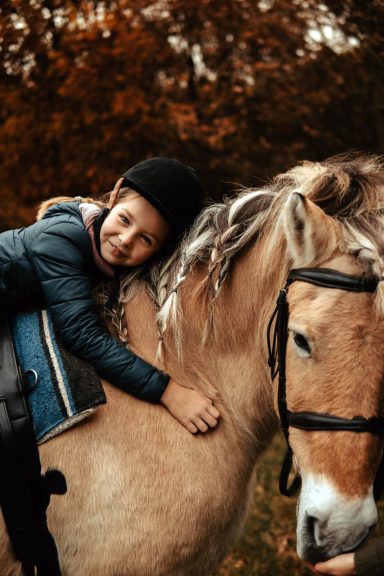 Reittherapie Ivenack Ein kleines Mädchen lehnt über den Hals eines Pferdes und ist glücklich.