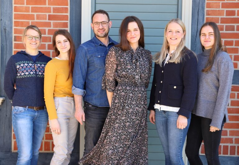 Team ERGOtherapeutische Praxis Sechs Mitarbeiter:innen stehen lächelnd vor einer Hauswand