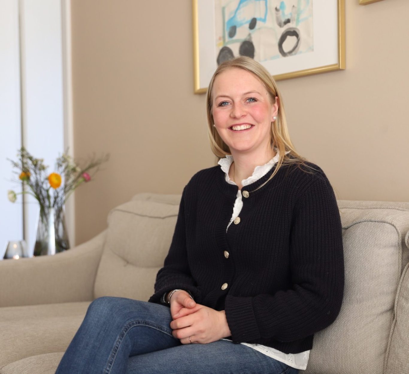 Reittherapie Ivenack Reittherapeutin Franziska sitzt lächelnd auf einem Sofa.