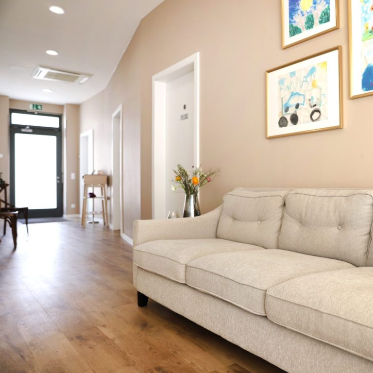 Ergotherapeutische Praxis Robert Steiger Ein Wartebereich mit Sofa und Deko in einem Flur