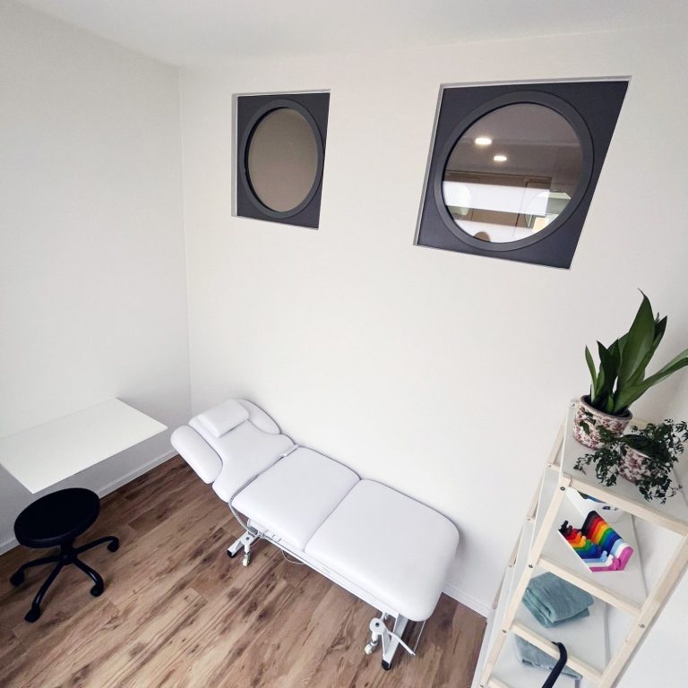 Massageraum Ergotherapie Eine Liege, ein Regal mit weiteren Behandlungsutensilien für Massage.